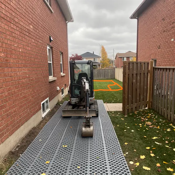 Mini excavator entering narrow Guelph backyard gate